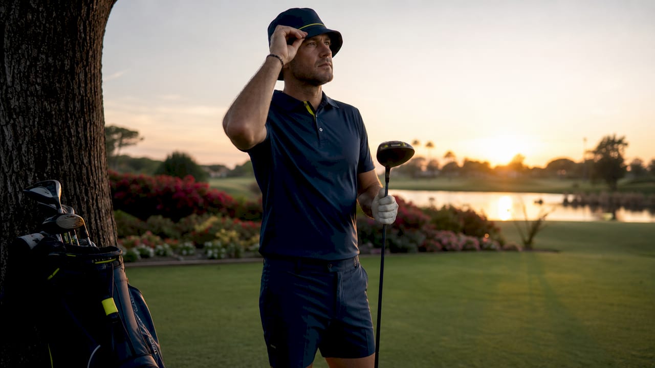 Male golfer adjusting cap on sunny golf course